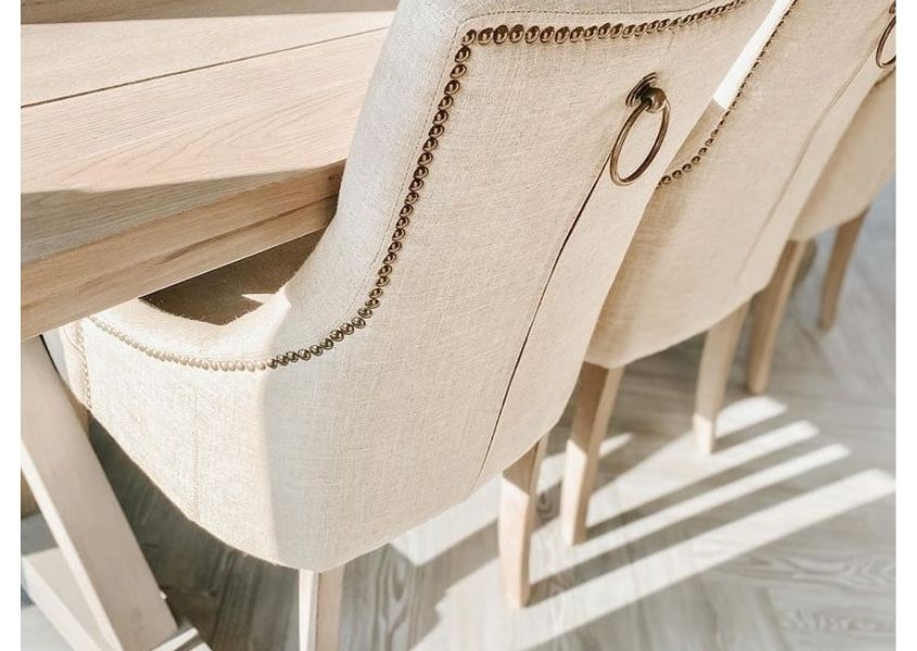Cream upholstered dining chair with buttoned back and metal handle detailing