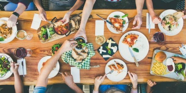 Large wood dining table with food and arms
