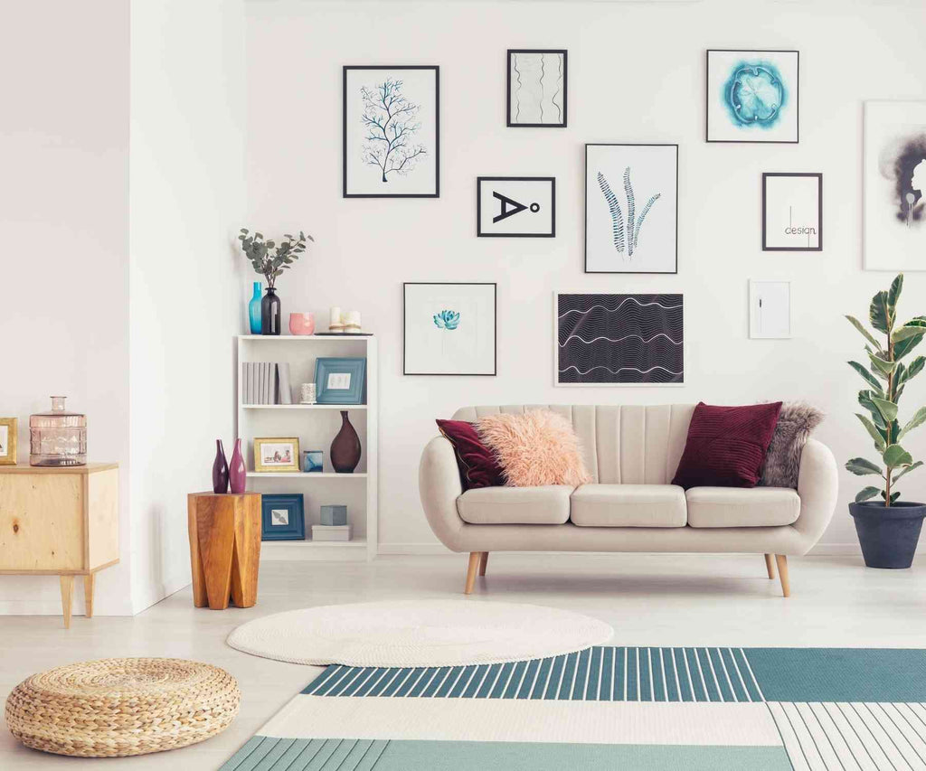 Living room with grey sofa and layered rugs with display of prints on wall