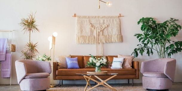 brown leather sofa with large wall hanging and green plant