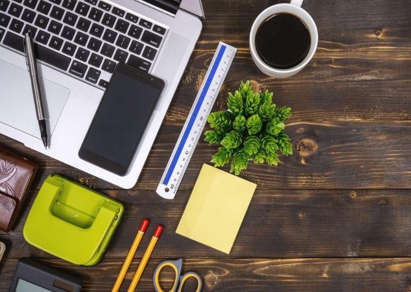 Rustic wood table with laptop, coffee, pens and other work accessories