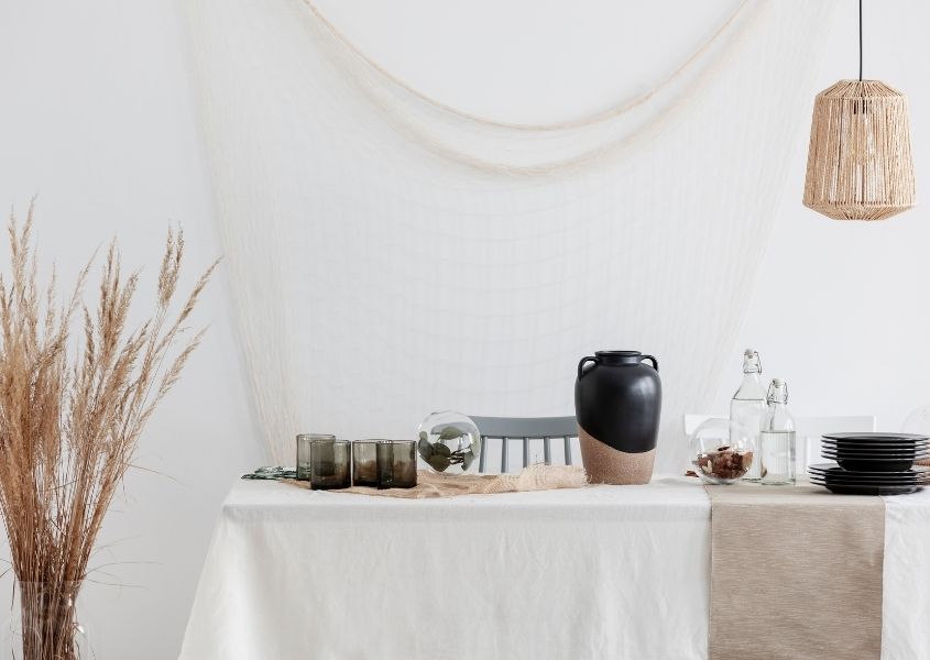 rustic dining table with white table cover, pampas grass and rattan hanging pendant light