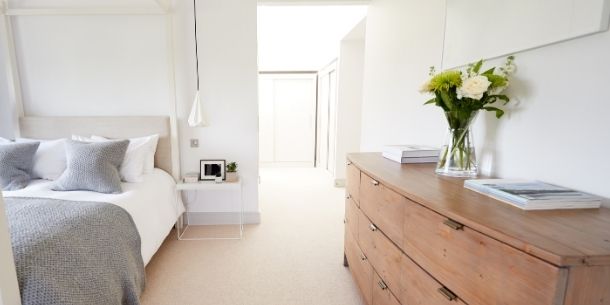 Large reclaimed wood chest of drawers in bedroom with white four poster bed