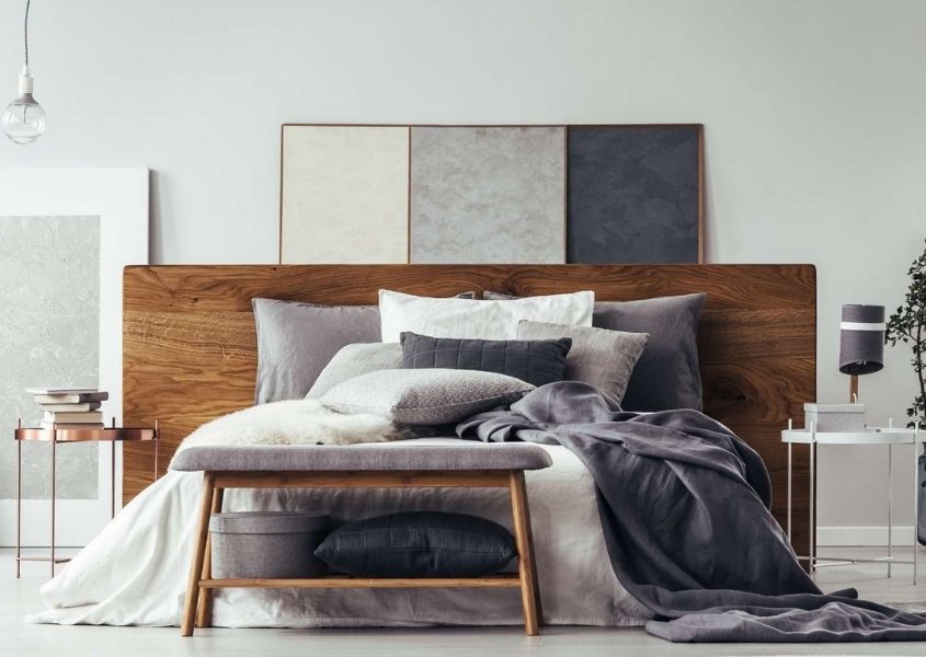 Grey bedroom with wooden bed and stool and at end of bed with white and grey covers