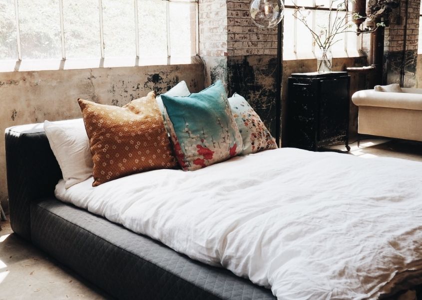 Brown leather king size bed frame with white covers in industrial style room