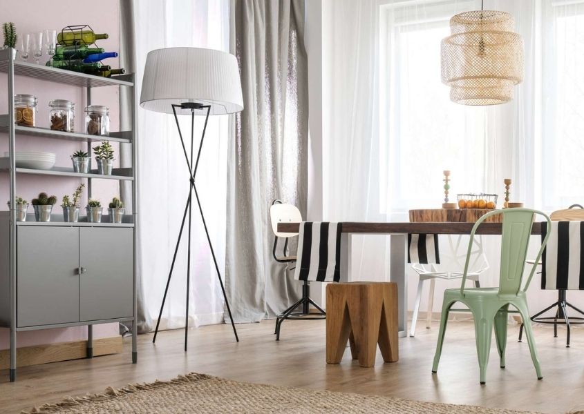 Grey bookcase with cupboard doors in living room with floor lamp and dining table