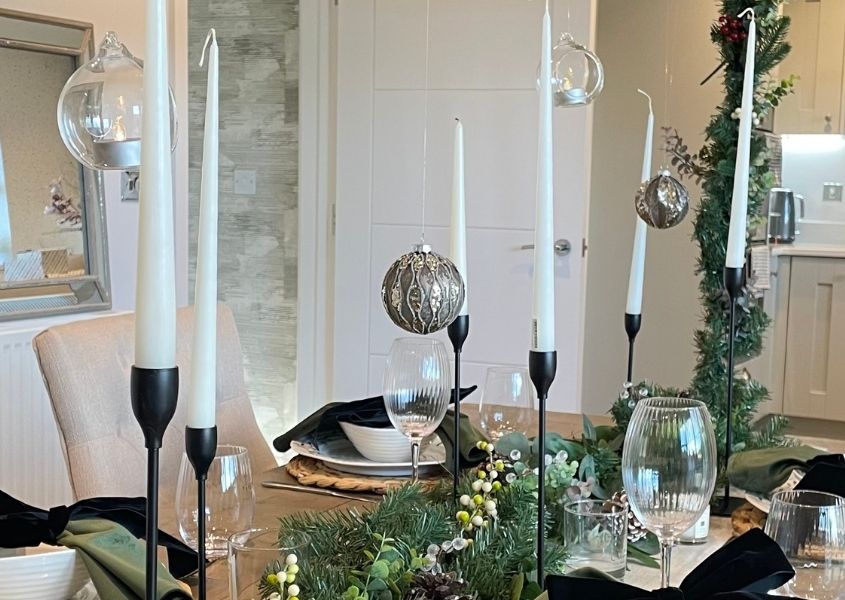 hanging Christmas baubles and tea lights over rustic dining table