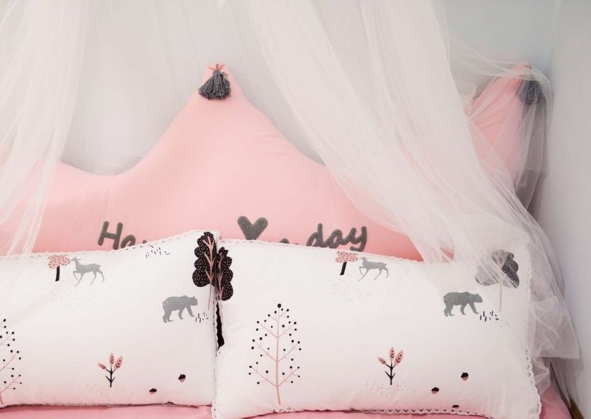 Pink child's bed with sheer fabric draped above
