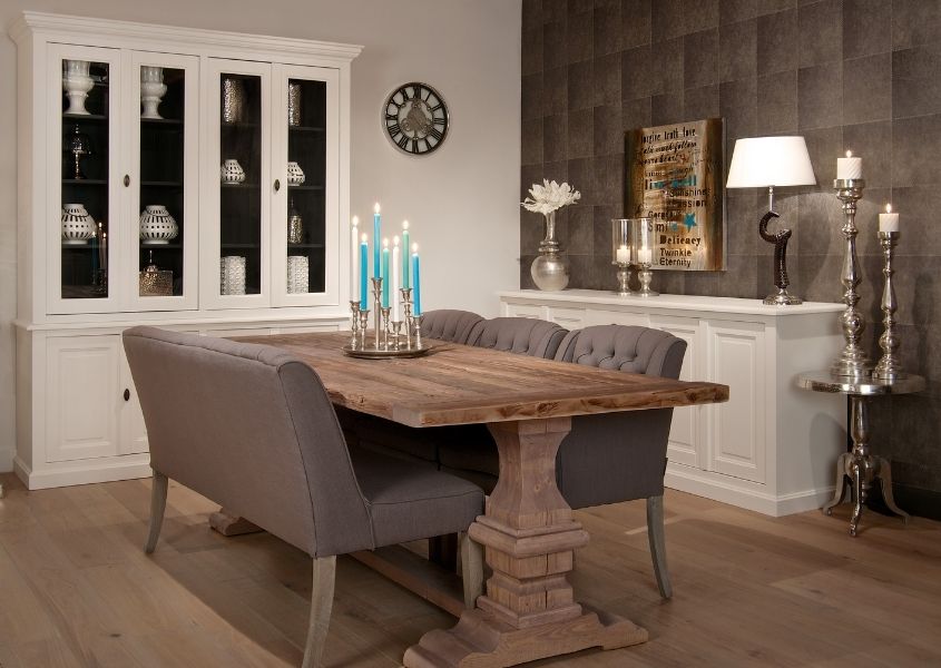 Farmhouse dining table with grey fabric chairs and large white display cabinet