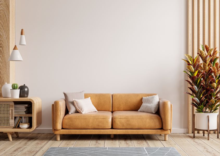 brown leather sofa with tall house plant and wooden side table