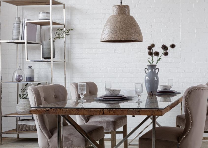 Large woodchip pendant light over reclaimed wood dining table with velvet dining chairs