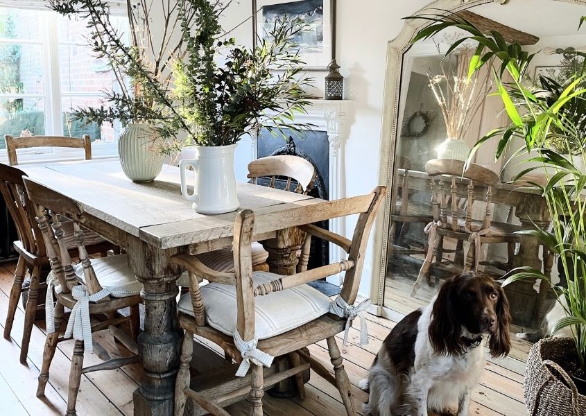 rustic dining table with wooden dining chairs and large vases of flowers