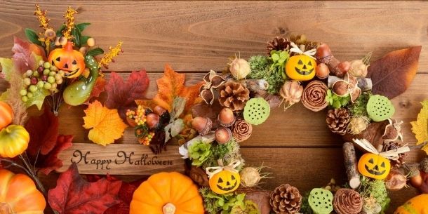 Halloween decorations including wreath with small pumpkins and pine cones with Happy Halloween wood sign