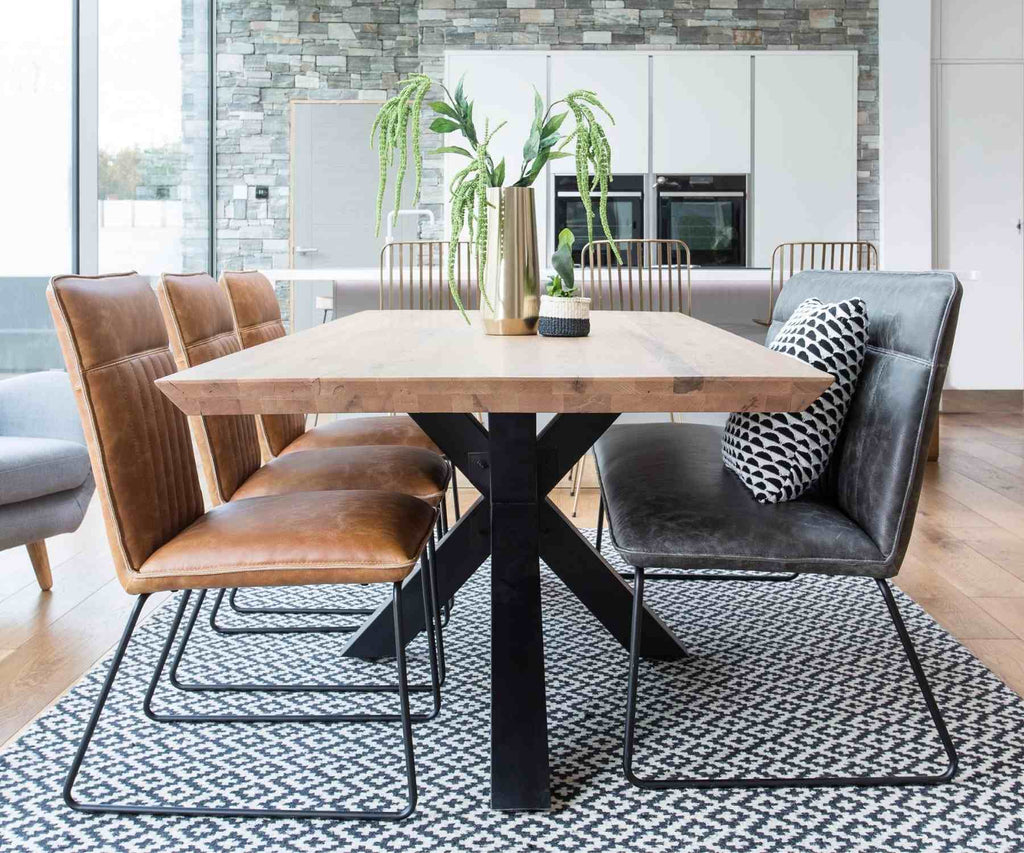Industrial dining table with black spider legs and faux leather bench and chairs