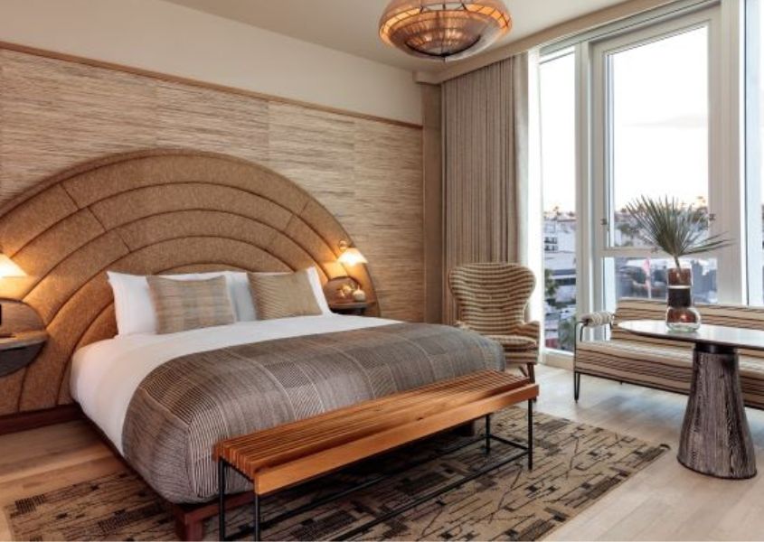 king size bed with curved fabric headboard and wooden bench