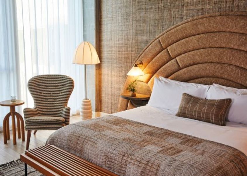 Fabric armchair next to king size bed with curved fabric headboard