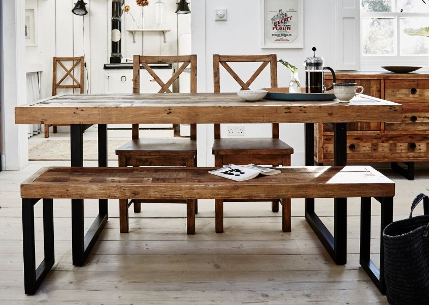 Industrial dining table with black steel legs and matching wooden dining bench in a bright white room