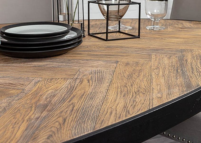 Close up of parquet dining table with black steel frame and small plate on table