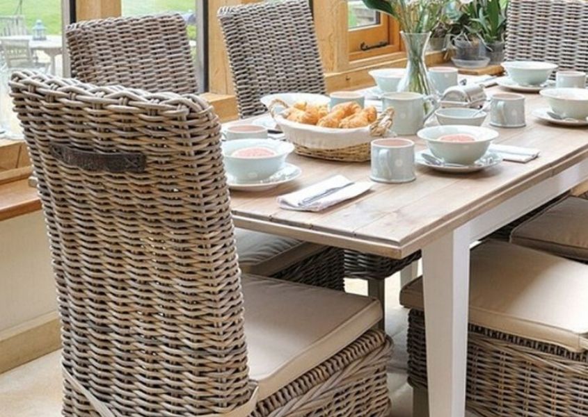 Wooden dining table with white painted legs and high back rattan dining chair