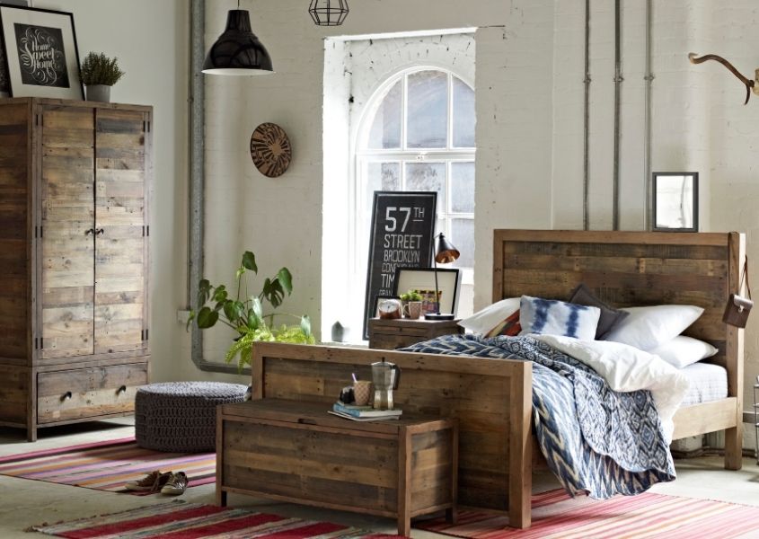Bedroom with large wooden bed, matching blanket box and double wardrobe and red rug on floor