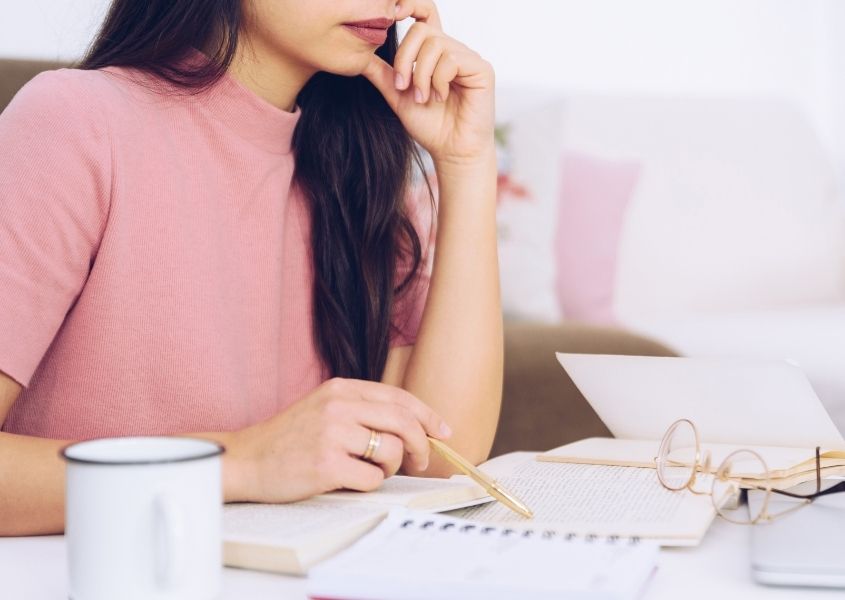 Girl in pink jumper at a desk for tips to create a revision-friendly study space blog