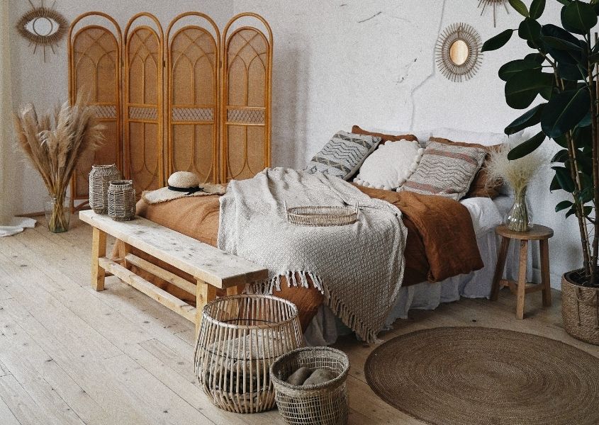 Wooden bench at bottom of double bed in boho style