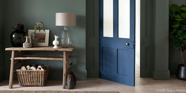 rustic console table with wicker log basket below and glass table lamp on table top