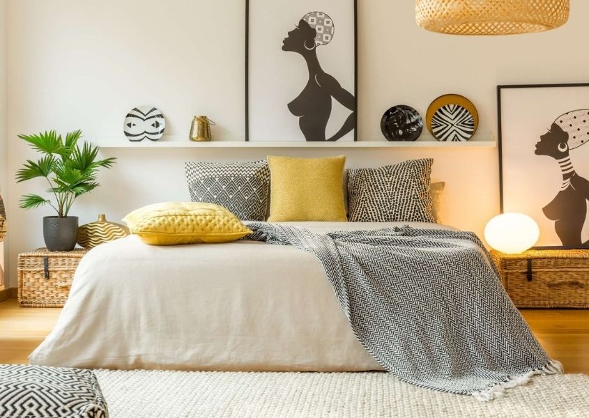 Bedroom featuring large bed with light and dark grey covers and cushions and artwork on the wall