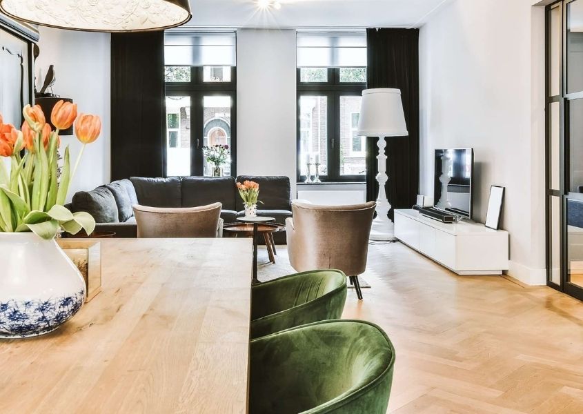 Open plan living and dining room with wooden dining table and green velvet dining chairs