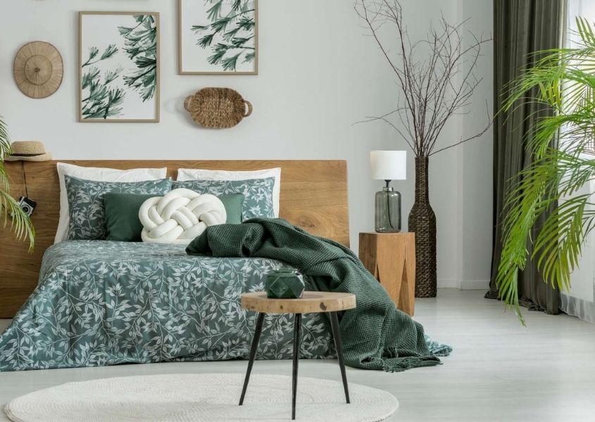 Bedroom with wooden bed and green covers, green curtains and green plants