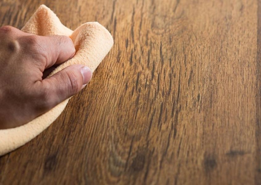 Close up of rustic wood with hand wiping wood with cloth
