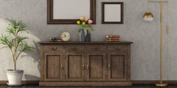 Large sideboard in rustic wood with gold floor lamp and tall green plant on the side