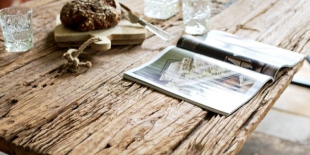 Close up of reclaimed wood dining table with open magazine
