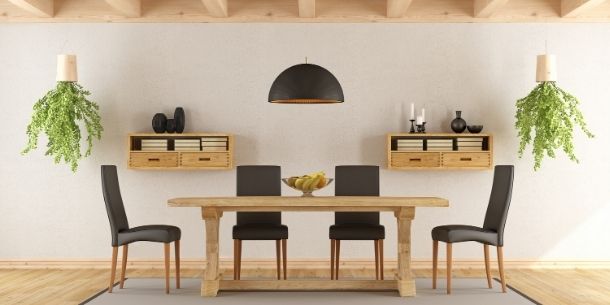 Large rustic dining table with dark dining chairs and hanging green plants from wooden beam ceiling
