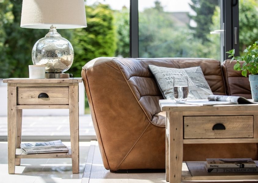 reclaimed wood side table and rustic coffee table next to brown leather sofa