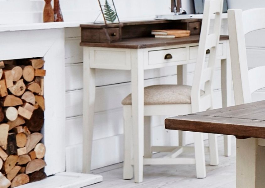 White painted reclaimed wood writing desk with natural wood top, next to pile of logs in fireplace