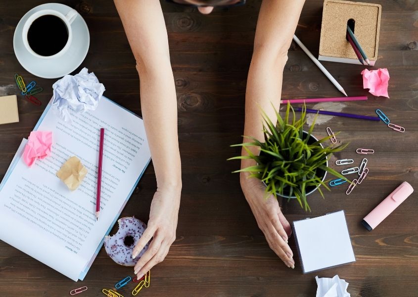 woman clearing rustic wood desk of paper